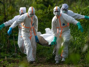 In this Sunday, July 14 fike, 2019 photo, burial workers dressed in protective gear carry the remains someone that died of Ebola, in Beni, Congo.