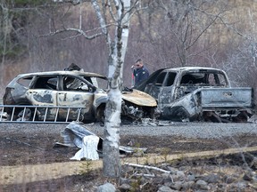 An RCMP investigator inspects vehicles destroyed by fire at the residence of Alanna Jenkins and Sean McLean, both corrections officers, in Wentworth Centre, N.S. on Monday, April 20, 2020.