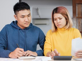 Stressed Asian couple serious calculate home financial bill budget on table in kitchen at new house.