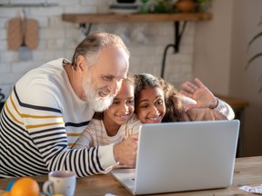 Grey-haired bearded man and his granddaughters talking online