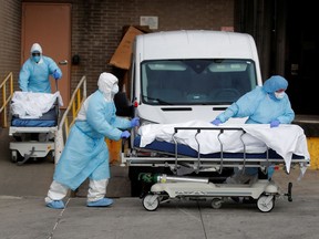 Health-care workers wheel the bodies of people who have died from the Wyckoff Heights Medical Center in Brooklyn, N.Y., on April 2, 2020, amid the COVID-19 coronavirus pandemic.