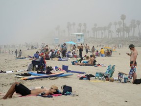 People sit in groups at Huntington City Beach during the outbreak of the coronavirus disease (COVID-19) in Huntington Beach, Calif., on April 25, 2020.