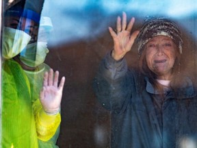 Joyce (no last name given) waves at passing cars honking their horns for support at Orchard Villa Retirement Residence after several residents died of COVID-19 in Pickering, Ontario, April 25, 2020.
