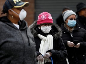 People wearing protective masks wait in line for donated food at the Queensbridge Houses, a New York City Housing Authority complex, in the Queens borough of New York on April 21.