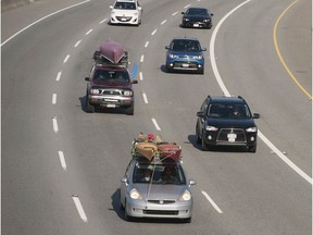 Vehicles carrying kayaks and bikes travel eastbound on the Trans-Canada Highway through Coquitlam, B.C. on Friday, April 10. Health officials have strongly advised people to stay home during the COVID-19 pandemic.