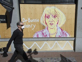 A man walks past a painted COVID-19 mural of Dr. Bonnie Henry on Tuesday along Powell Street in Vancouver.