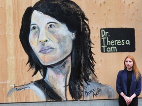 Artist Breece Austin with her portrait of Canada's chief public health officer Dr. Theresa Tam on the boarding put up outside a Gastown print shop.