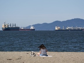 A woman enjoys the sunshine while sitting at Kits Beach in Vancouver on Monday.
