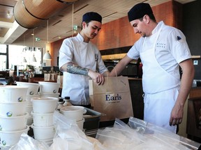 Evan Chong (left) and Matthew Luchor pack take out bags as Earls Restaurants has switched into Earls Grocery to repurpose goods in the restaurant supply chain for home consumers.