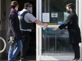 A security guard watches for customers leaving before allowing the next person to enter after applying a hand sanitizer to those entering at a LCBO store on Thursday April 9, 2020.