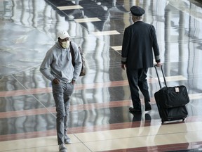 A traveller wears a face covering as he walks through a mostly empty terminal at Ronald Reagan Washington National Airport, May 5, 2020 in Arlington, Virginia.