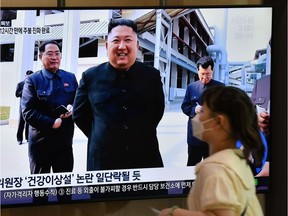 TOPSHOT - A woman walks past a television news screen showing a picture of North Korean leader Kim Jong Un attending a ceremony to mark the completion of Sunchon phosphatic fertiliser factory, at a railway station in Seoul on May 2, 2020. - North Korea's Kim Jong Un has made his first public appearance in nearly three weeks, state media reported on May 2, following intense speculation that the leader of the nuclear-armed nation was seriously ill or possibly dead. (Photo by Jung Yeon-je / AFP)