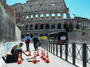 A worker marks out his working space on Via dei Fori Imperiali near the Colosseum in central Rome on May 4, 2020 as Italy starts to ease its lockdown aimed at curbing the spread of COVID-19.