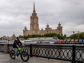 A woman wears a protective face mask as she rides a bike along the Moskva river embankment in central Moscow on May 10, 2020, during a strict lockdown in Russia to stop the spread of the novel coronavirus COVID-19.