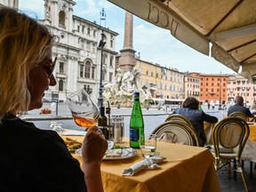 A woman drinks wine at a restaurant's terrace on Piazza Navona in central Rome on May 18, 2020, the day restaurants reopened after a two-month COVID-19 shutdown.