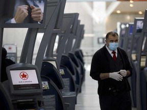 A gate agent wearing a protective mask and gloves at Air Canada check in terminals at Toronto Pearson International Airport.