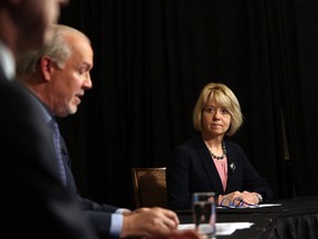 Provincial Health Officer Dr. Bonnie Henry and Health Minister Adrian Dix look on as Premier John Horgan discusses reopening the province's economy in phases on May 6, 2020.