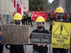 Hong Kong anti-extradition bill protesters hold signs as pro-China counter-protesters gather behind them during opposing rallies in Vancouver last August.