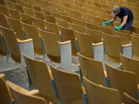 A worker is seen cleaning the seats of the auditorium at Eric Hamber Secondary school in Vancouver, B.C., Monday, March 23, 2020. Schools in British Columbia are set to reopen Monday.