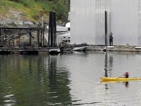 A kayaker paddles past the burned fuel dock at the North Saanich Marina on Monday.