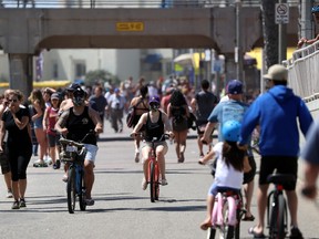 People ride and walk on a path along beach amid the coronavirus pandemic on May 15, 2020 in Huntington Beach, California. Beaches across the state have started to reopen with rules in place such as maintaining social distancing and restrictions against lying or sitting down on the beach in order to slow the spread of COVID-19.