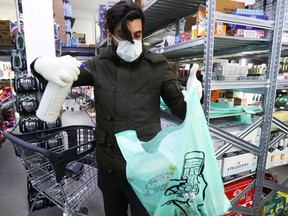 A worker sanitizes a plastic bag of groceries before being delivered to the customer, amid the coronavirus disease outbreak.