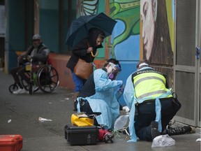 Ambulance paramedics help a man suffering a drug overdose on Columbia Street in Vancouver's Downtown Eastside. After being injected with Naloxone, the man woke up and walked away.