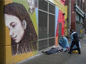 Ambulance paramedics help a man suffering a drug overdose on Columbia Street in Vancouver on May 2, 2020.