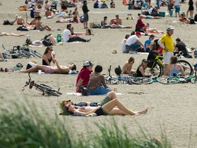 People enjoy the weather, somewhat apart, at English Bay in Vancouver on May 10.