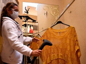 An employee wearing a protective face mask steam cleans a blouse during the clothing store's reopening in Namur, Belgium, on May 11, 2020, on the first day of a partial lifting of the lockdown introduced two months ago to fight the spread of the novel coronavirus.