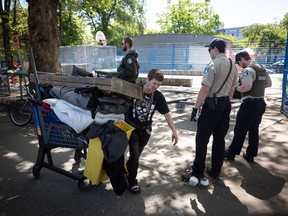 Park rangers stand by as Kim Berg moves her belongings out of a homeless camp at Oppenheimer Park just before a 12 p.m. deadline for the park to be vacated, in the Downtown Eastside of Vancouver, on Saturday, May 9, 2020. Vulnerable and homeless people across British Columbia could soon receive a smartphone to access support services and to stay connected with friends and family while practising physical distancing.