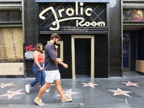 People walk past the historic Frolic Room bar which is shuttered along Hollywood Boulevard amid the COVID-19 pandemic on June 29, 2020 in Los Angeles, California. Bars in Los Angeles County were ordered to close again by Governor Gavin Newsom amid a new surge of coronavirus cases.