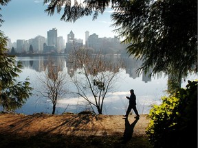 A man walks along the path around Lost Lagoon in Stanley Park on a beautiful sunny morning.
