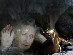 A woman visits with her mother through the window of a care facility in Ontario.