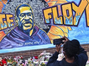 A person takes a photo of a mural in memory of George Floyd with flowers and other memorial items below, on a wall of the Cup Foods store on May 29 in Minneapolis, Minn.