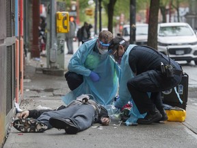 cVancouver, BC: MAY 02, 2020 --  Ambulance paramedics help a man suffering a drug overdose on Columbia Street in Vancouver, BC's Downtown Eastside Saturday, May 2, 2020. After being injected with Naloxone by the paramedics the man woke up and walked away.