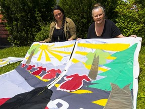 Ursula Andrade and Kaytee Kilgour with the arpilleras that are being installed Saturday outside St. Andrew’s-Wesley United Church.
