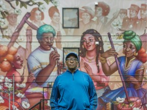 Lama Mugabo stands in front of a mural by Ejiwa (Edge) Ebenebe depicting the life of Hogan's Alley, on the wall of Nora Hendrix Place in Vancouver on June 30.