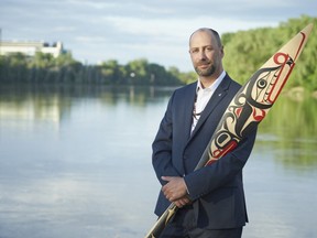 Ry Moran, a member of the Red River Metis in Manitoba, holds a reconciliation paddle carved by Carey Newman. Moran will take on a newly created role in the fall as UVic reconciliation librarian.