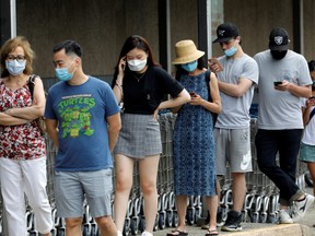 People wear protective face masks outside at a shopping plaza after New Jersey Governor Phil Murphy said he would sign an executive order requiring people to wear face coverings outdoors to prevent a resurgence of the coronavirus disease (COVID-19), in Edgewater, New Jersey, U.S., July 8, 2020.