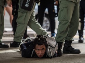 Riot police detain a man as they clear protesters taking part in a rally against a new national security law in Hong Kong on July 1, 2020, on the 23rd anniversary of the city's handover from Britain to China. Hong Kong police made the first arrests under Beijing's new national security law on July 1 as the city greeted the anniversary of its handover to China with protesters fleeing water cannon.