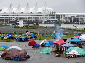 A man walks through a homeless camp where approximately 150 people are living at a parking lot on Port of Vancouver property adjacent to Crab Park, in Vancouver on June 10, 2020.