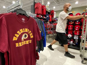 An employee passes  Washington Redskins football shirts for sale at a sporting goods store in the U.S. Pressure from sponsors and political groups is mounting for the NFL team to change its name.
