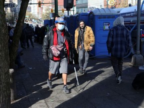 A man wearing a protective mask walks past portable toilets set up along Hastings Street following the closure of the Carnegie Community Centre back in March.