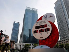 A man wearing a protective mask walks past a countdown clock for the Tokyo Olympic Games in Tokyo, Japan, on June 4, 2020.