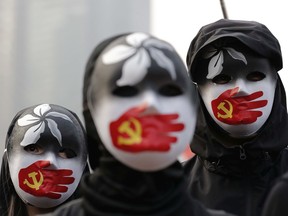 People wearing masks stand during a rally to show support for Uighurs and their fight for human rights in Hong Kong, Sunday, Dec. 22, 2019.