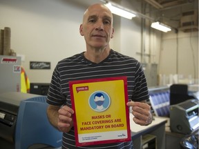 Mark Barker holds one of the new updated signs being placed at TransLink facilities.