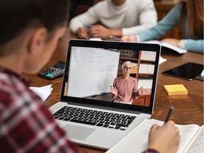 Teacher explaining lesson in video call while girl taking notes. Rear view of university student understanding concepts online while making notes. Young woman studying on computer and writing on notebook sitting in college library.