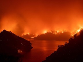 Flames surround Lake Berryessa during the LNU Lightning Complex fire in Napa, Calif., on Aug. 19, 2020. Thousands of people fled their homes in northern California as hundreds of fast-moving wildfires spread across the region.