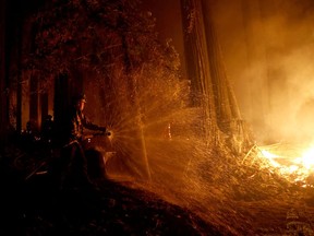 Firefighter Anthony Quiroz douses water on a flame as he defends a home during the CZU Lightning Complex Fire in Boulder Creek, Calif., on Aug 21, 2020.